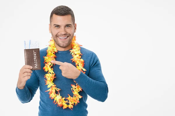 Young smiling man pointing on passport with tickets posing isolated on white wall background — 스톡 사진