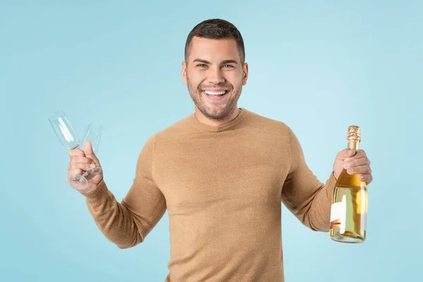 Happy man holding goblets and champagne bottle over blue background — 스톡 사진