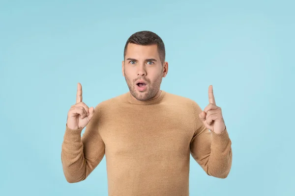 Aufgeregter Mann zeigt mit dem Finger auf Kopierraum auf blauem Hintergrund — Stockfoto