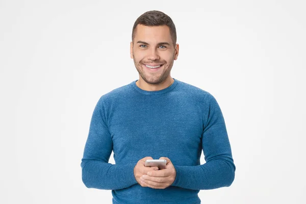 Portrait of smiling young man holding mobile phone isolated over white background — ストック写真