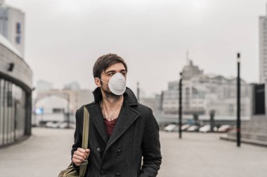 Virüsü önlemek için hijyenik maske takan genç bir adam. Çevre kavramı