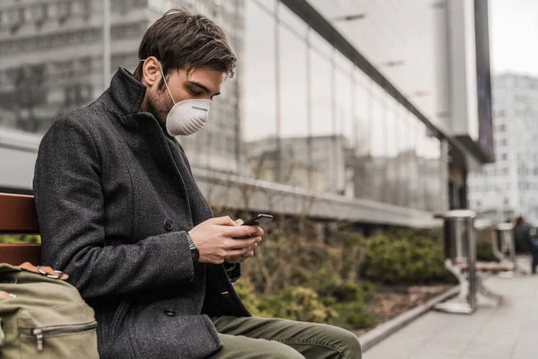 Adam, virüsü önlemek ve cep telefonu kullanırken korunmak için maske takıyor