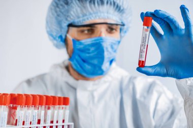 Koronavirüs enfeksiyonlu kan örnekleri için yüz maskeli doktor vakum tüpleri.