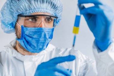 Koronovirüs araştırması yapan test tüpü beyaz arka planda virolojistin elinde.