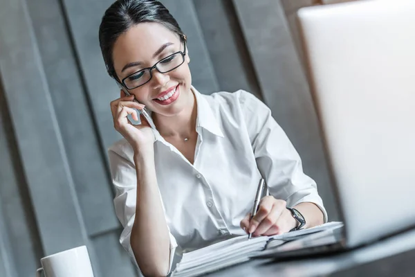 Jovem Mulher Bonita Alegre Óculos Falando Telefone Usando Laptop Enquanto — Fotografia de Stock