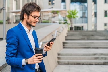 İş adamı dışarıda kahve molası verirken akıllı telefon kullanıyor.