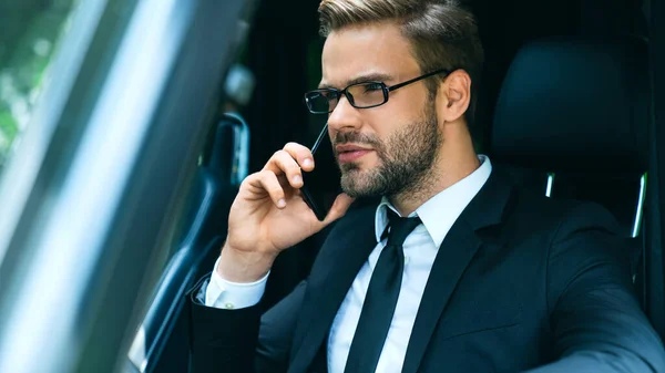 Przystojny Młody Biznesmen Pełnym Garniturze Rozmawiający Przez Smartfon Podczas Jazdy — Zdjęcie stockowe