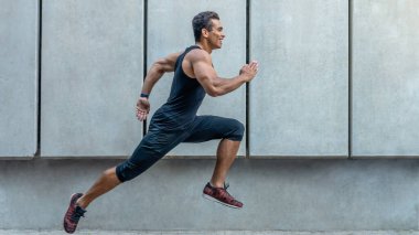 Spor elbiseli yakışıklı genç adam tam boy atlarken