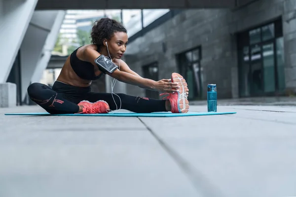 健身妇女 带耳机 在室外健身垫上锻炼和伸展身体 — 图库照片