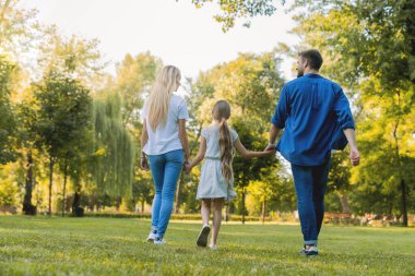 Ebeveyn ve güzel kızın şehir parkında eğlenip yürümelerini arka planda izlemek.