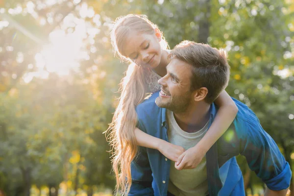 Close up of a man carrying his daughter on his back outdoors