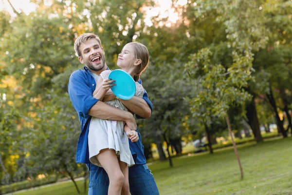 Feliz Padre Sonriente Abrazando Hermosa Hija Sonriente Con Frisby Las — Foto de Stock