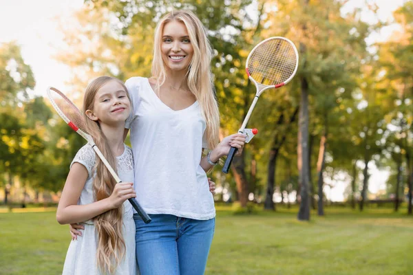 Linda Niña Abrazando Madre Con Raquetas Bádminton Aire Libre — Foto de Stock