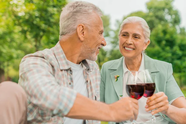 Portrait of beautiful senior couple drinking wine and enjoying time together while sitting outdoor