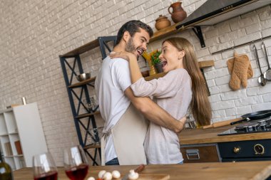 Yakışıklı adam ve çekici genç kadın yemek pişirirken eğleniyor ve dans ediyorlar.