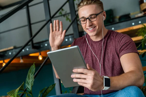 Pemuda Tersenyum Menggunakan Tablet Digital Dan Headphone Kantor Sambil Menyapa — Stok Foto