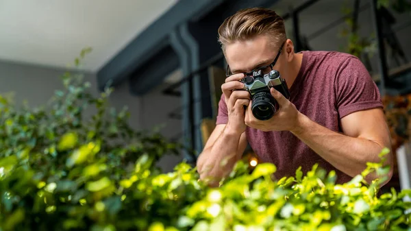 若い白人男性が温室内の光カメラで植物の写真を撮る — ストック写真
