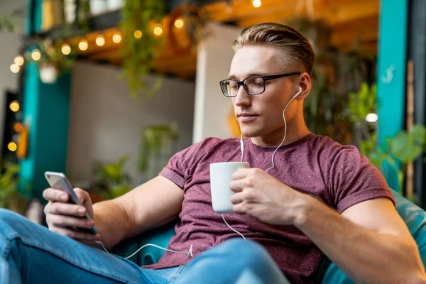 Kulaklıklı Genç Adam Yerinde Mola Verirken Telefonunu Kullanıyor Kahve Içiyor — Stok fotoğraf