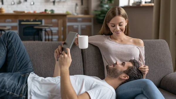 Dijital Tablet Kahve Bardağıyla Kanepede Uzanmış Genç Mutlu Bir Çift — Stok fotoğraf
