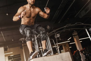 Genç bir adam spor salonunda egzersiz yapıyor. Kutu atlayışı alıştırması