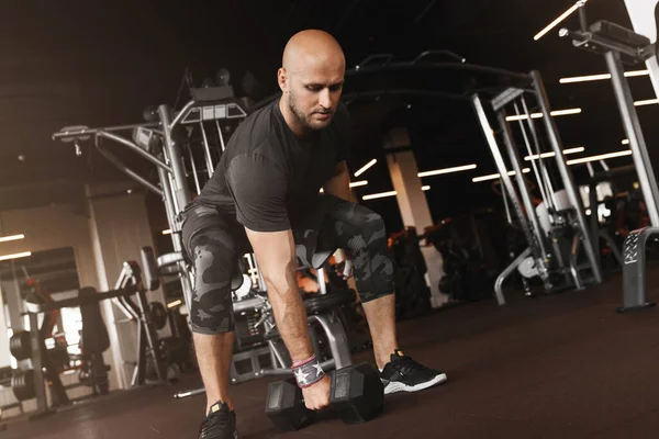 Practicing functional training of fit athlete doing dumbbell squats at gym