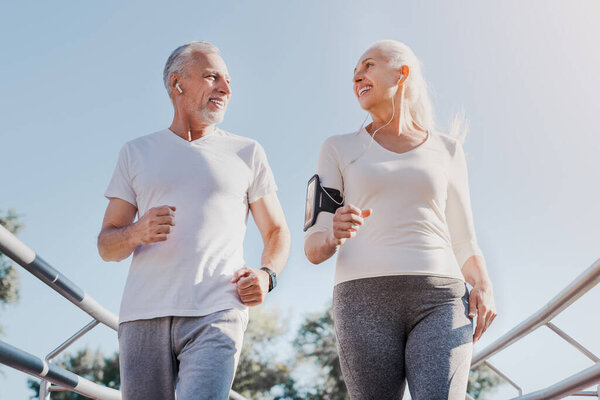 Close up of healthy smiling mature couple jogging in the city at