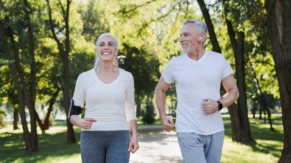 Älterer Mann Und Alte Frau Mit Kopfhörern Joggen Gemeinsam Draußen — Stockfoto