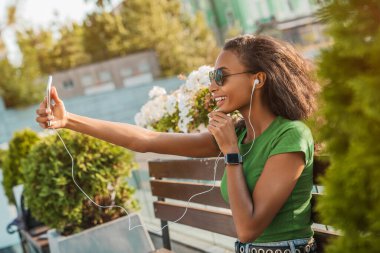 Genç bir kadının dışarıda otururken cep telefonuyla yaptığı görüntüler. Çevrimiçi iletişim kavramı