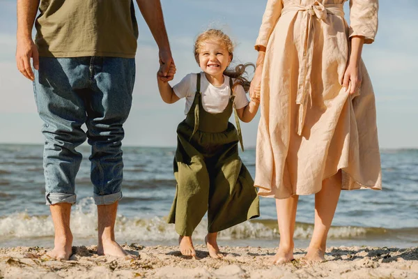 Cropped image of young family standing on the beach with happy cute girl