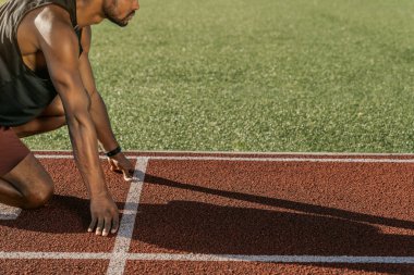 Yan görüş, koşucunun güneş gölgesi olan stadyumda yarışa başlamak üzere olduğunu gösteriyor.