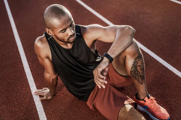 Joven Deportista Sentado Pista Atletismo Mirando Smartwatch — Foto de Stock