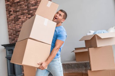 Genç adam taşınırken bütün kutuları taşımaya çalışıyor.