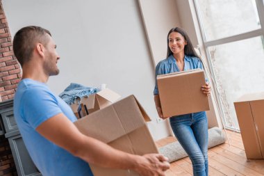 Genç bir çift yeni bir eve karton dolusu gerekli eşyalar taşıyor.