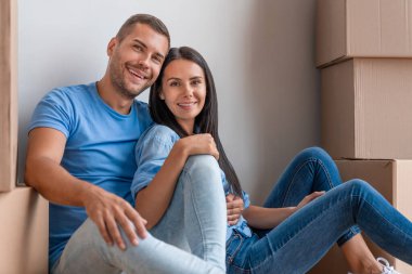 Ev aldıktan sonra duvarın yanında oturan mutlu çift.