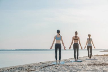 Sahilde yoga yapan bir grup kadın.