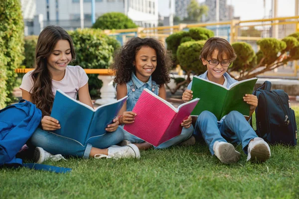 Lindos Niños Felices Escuela Con Mochilas Cuadernos Sentados Parque Hierba — Foto de Stock