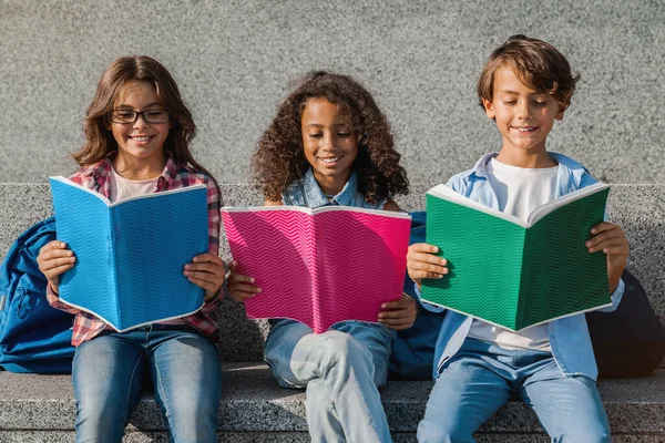 Primer Plano Niños Sonrientes Escuela Con Mochilas Sosteniendo Cuadernos Divirtiéndose — Foto de Stock