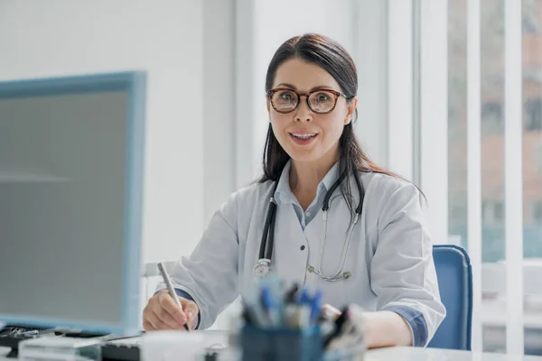 Doctora Que Trabaja Escritorio Oficina Sonríe Cámara —  Fotos de Stock