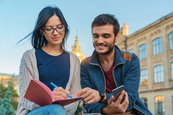 Jovens Estudantes Sentados Livre Olhando Para Telefone Celular Enquanto Sorrindo — Fotografia de Stock
