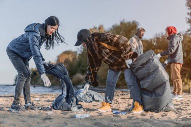 Gönüllü konsepti. Gençler dışarıda çöp topluyor.