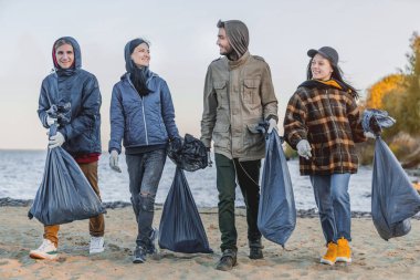 Bir grup arkadaş plajda plastik topluyor.