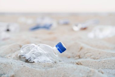 Plajdaki plastik çöpleri yakından çek.