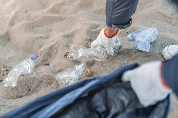Man collects plastic from the beach in bag. Ecology protection concept