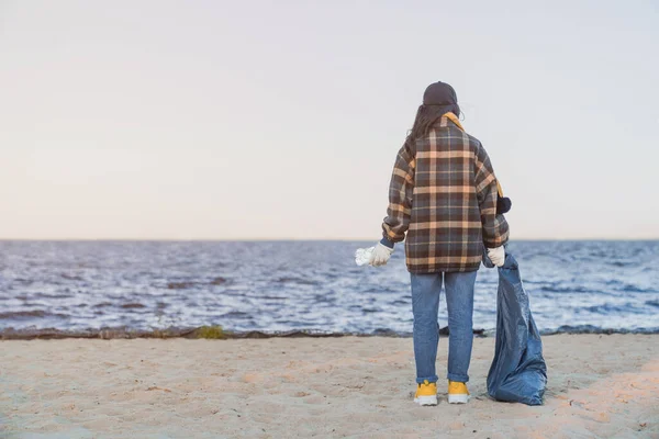 Plajda Duran Genç Bir Kızın Arka Manzarası Elinde Çöp Torbası — Stok fotoğraf
