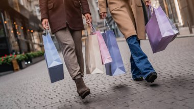 Alışveriş torbalarıyla caddede yürüyen genç kadınların önü kesilmiş.