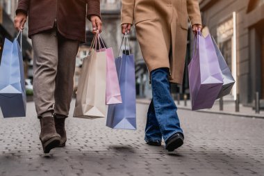 Alışveriş poşetleriyle sokakta yürüyen genç kadınlar.