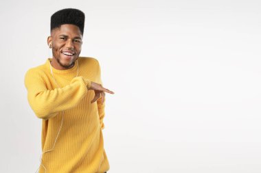 Kulaklık ve cep telefonu ile dans eden mutlu Afrikalı bir adamın portresi. Beyaz arka planda izole edilmiş heyecanlı.