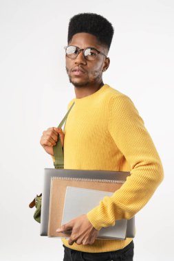 Gözlüklü, sırt çantalı, dizüstü bilgisayarı beyaz arka planda olan üniversite öğrencisinin dikey görüntüsü.