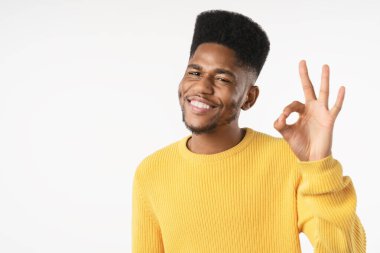 Portrait of smiling young man showing okay gesture isolated on white background