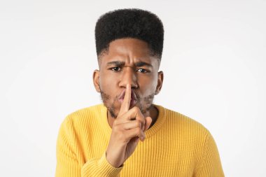 Koyu tenli bir adam beyaz arka planda izole edilmiş sessiz bir jest yapar.